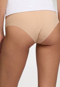 Slip classico color carne realizzato in tessuto morbido ed elastico. Presenta una vita a media altezza e bordi senza cuciture per un comfort ottimale.
