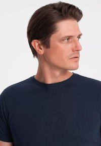 Námorně modré tričko s kulatým výstřihem vyrobené z žebrované tkaniny, s krátkými rukávy a přiléhavým střihem, s hladkou texturou a minimálními detaily.