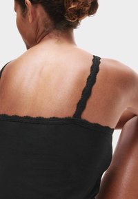 Zwarte cami met dunne bandjes en een gegolfde kantafwerking, met een gladde textuur en een aansluitende pasvorm.