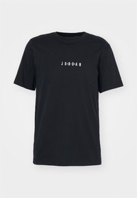 Schwarzes T-Shirt mit kurzem Arm und Rundhalsausschnitt, mit weißen Buchstaben, die "JORDAN" in gleichmäßigem Abstand auf der Brust zentriert angeben.