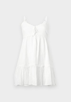 White sleeveless dress with lace trim, tie detail at the bust, tiered ruffled hem, and floral pattern on lightweight fabric.