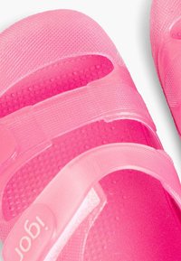 Transparent pink sandals with multiple textured straps and patterned footbed, showcasing a lightweight design for comfort and flexibility.