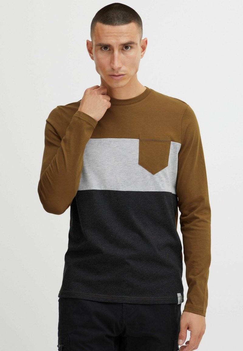 Dugi rukav T-shirt izrađen od pamuka, s smešnim gornjim delom, sivo srednjim delom i crnim donjim delom, s džepom na grudima i teksturiranom tkaninom.