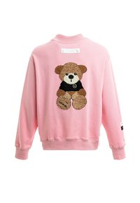 Sudadera rosa con un aplique texturizado de un oso de peluche en marrón y negro en la parte posterior. Puños y dobladillo acanalados con una etiqueta cerca del escote.