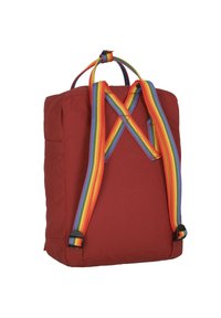 Roter Stoff-Rucksack mit Regenbogenfarbenen Riemen, rechteckiger Form und einer Seitentasche für zusätzlichen Stauraum. Schlichtes Design mit minimalen Beschlägen.