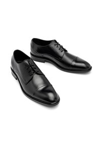 Chaussures habillées en cuir noir avec un design élégant, bout pointu et fermeture à lacets. Présentent une texture lisse et des détails de couture subtils.