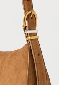 Curea de geantă din piele întoarsă maro cu un cârlig metalic auriu și accente argintii, având o textură moale și margini curate.