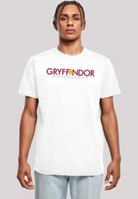 Bílý bavlněný tričko s nápisem "GRYFFINDOR" tučným červeným písmem, se žlutým emblémem lva nad textem. Krátké rukávy a klasický střih.