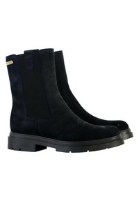 Bottes de cheville en suède bleu marine foncé avec des panneaux latéraux en élastique et des semelles en caoutchouc noir. Présentent une languette à l'arrière et une texture lisse.