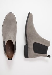 Šedé semišové kotníkové boty s elastickými bočními panely, nízkým blokovým podpatkem a poutkem vzadu. Hladký povrch a minimalistický design.