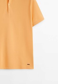 Oranges Polohemd aus strukturiertem Stoff, mit kurzen Ärmeln, einem Zwei-Knopf-Verschluss und einem kleinen Markenlabel am unteren linken Saum.