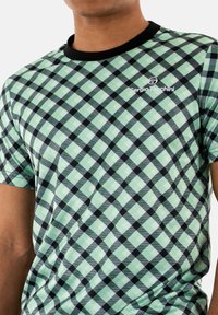 Camicetta a maniche corte con un motivo a scacchi verde menta e nero, dotata di un collo rotondo nero e di un piccolo logo bianco sul petto.