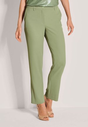 Grüne, maßgeschneiderte Hose aus glattem Stoff mit Knopfverschluss, geradem Bein und kombiniert mit nudefarbenen High-Heels.