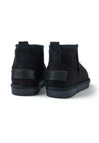 Stivaletti alla caviglia in suede nero con una finitura testurizzata, dotati di pannelli elastici sui lati, una linguetta e una suola in gomma con una leggera scolpitura.