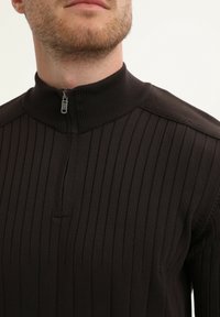 Zwarte geribbelde pullover met een halve rits kraag en een textuur gebreid patroon, met een aansluitend ontwerp en een gladde afwerking.