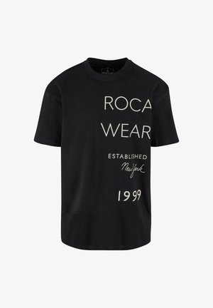 Fekete pamut póló, amelyen nagy fehér feliratok olvashatók: "ROCA WEAR," "ESTABLISHED," "New York," és "1999" különböző betűtípusokkal az elején.