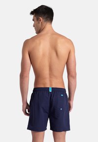 Pantaloncini da nuoto blu navy con cintura elastica, dettagli turchesi a contrasto e tasca posteriore con occhiello. Realizzati in tessuto leggero.