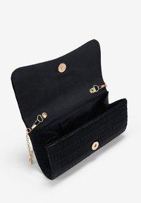 Bolso de mano negro con un exterior texturizado, herrajes dorados, cierre magnético y una correa de cadena. El interior cuenta con un compartimento espacioso.