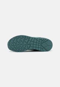Rubber shoe sole in teal, featuring textured tread with various geometric patterns for grip. Rounded toe and slightly raised heel.
