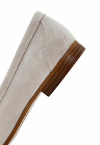 Chaussure plate en daim gris clair avec un bout arrondi et un petit talon en bois, présentant des coutures discrètes le long des bords.