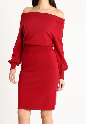 Rotes Off-Shoulder-Strickoberteil mit langen Puffärmeln, kombiniert mit einem taillierten roten knielangen Rock; weicher Strickstoff und gerippte Akzente.
