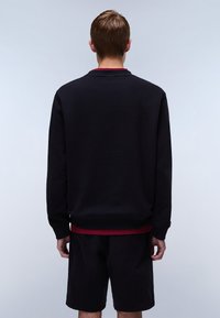 Sort sweatshirt med lange ærmer og ribbet kant, med en bordeaux accent ved kraven, parret med mørke shorts.