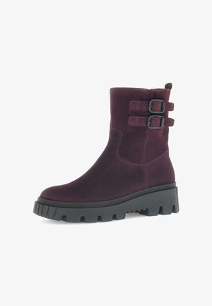 Burgundy suede ankle boot with two black buckle accents, chunky black rubber sole, and a smooth texture. Rounded toe design.