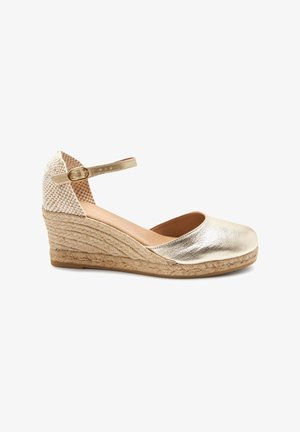Espadrille beige à talon compensé avec talon texturé, semelle tressée en jute, avant métallique et bride de cheville réglable avec boucle dorée.