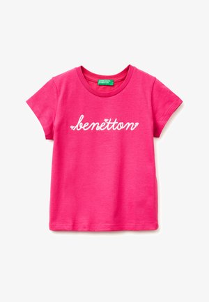 Jasnoróżowy T-shirt z krótkim rękawem, z białym tekstem "benetton" pisanym kursywą na przodzie oraz zieloną metką wewnątrz kołnierza.