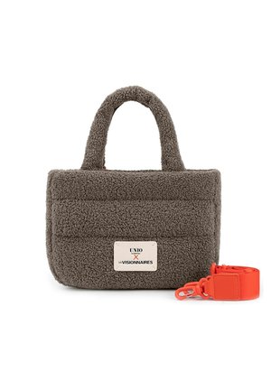 Kleine rechthoekige bruine sherpa handtas met twee handvatten en een wit label, naast een losgemaakt feloranje schouderriem met clips.