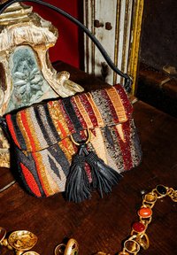 Borsa a mano con perline con motivo a righe in rosso, nero e oro; presenta un nappina in pelle nera e dettagli in metallo dorato.