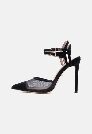 Chaussure noire à talon aiguilles pointu avec deux brides à la cheville, côtés en mesh, et talon stiletto fin sur fond blanc.