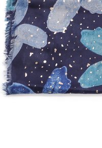 Sciarpa di stoffa blu e teal con sfondo navy, che presenta un motivo a foglia e puntini dorati; i bordi sfrangiati aggiungono texture.