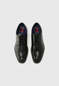 Zapatos de vestir de cuero negro con textura suave, diseño de punta redonda, cierre de cordones y forro interior azul en contraste.
