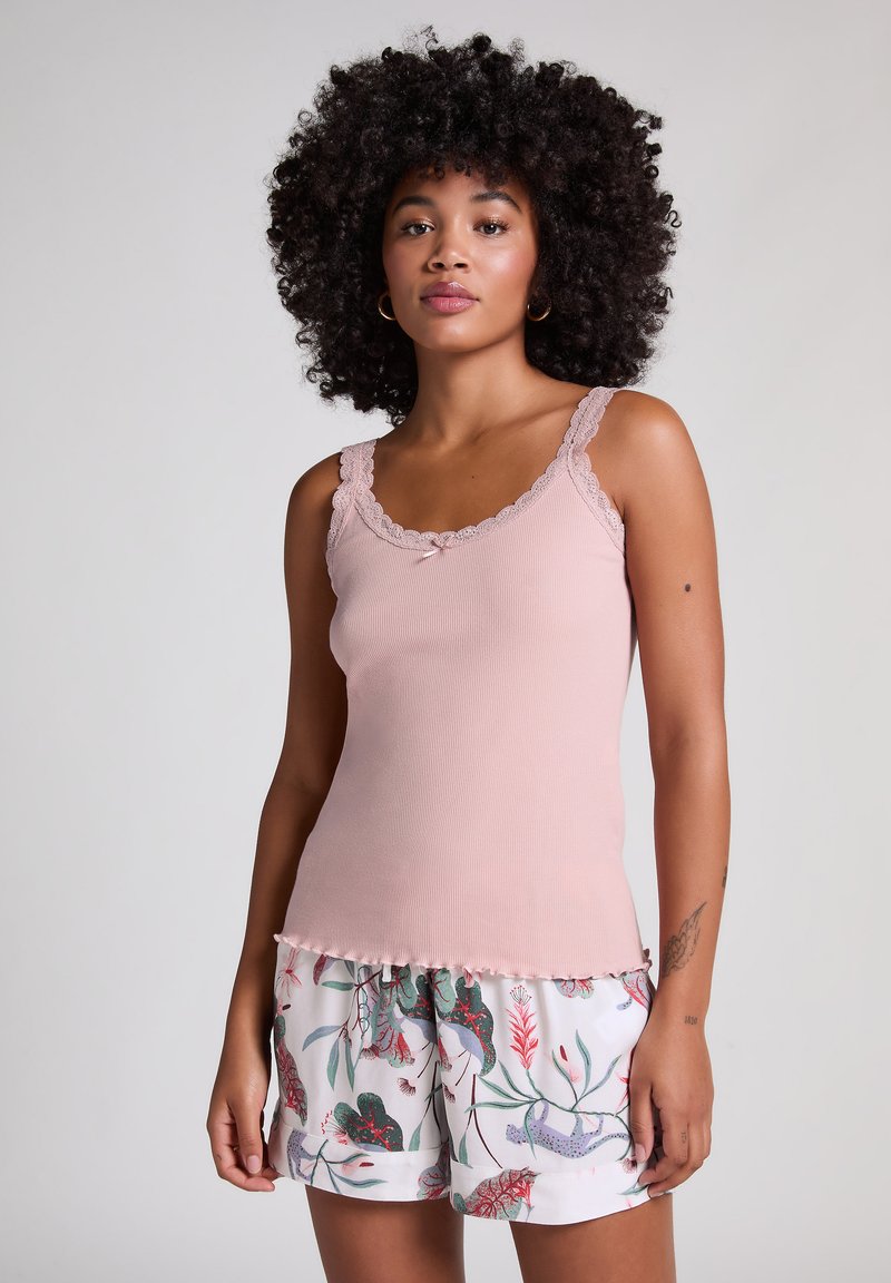 Débardeur rayé rose clair avec bord en dentelle et détail de nœud, associé à un short blanc à motifs floraux dans des nuances de vert et de rouge.