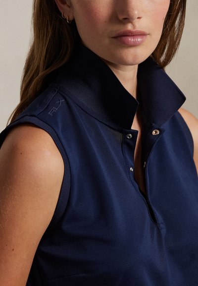 Μπλε σκούρο αμάνικο πόλο με ψηλό γιακά, με κλείσιμο με κουμπιά μπροστά και διακριτική λεπτομέρεια λογότυπου στον γιακά. Ομαλή υφή υφάσματος.