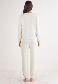 Lichtgrijze loungewear set met een losse pasvorm; het sweatshirt heeft ribgebreide mouwen en onderrand, terwijl de broek elastische boorden heeft voor extra comfort.