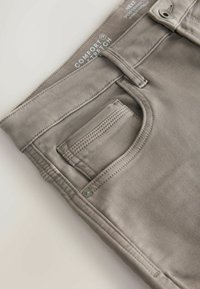 Hallid puuvillane segu, mugava venivusega hallid püksid, millel on eesmine tasku ja õmblemise detailid. Näha on metallnupp ja tõmblukk.