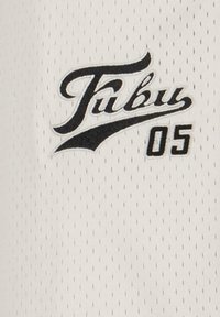 Bela mrežasta športna majica z napisom "Fubu" v črni pisavi in številko "05" v bold črni pisavi. Strukturirana površina z majhnimi perforacijami.