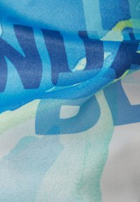 Satinstoff mit einem Farbverlauf von Blau- und Grüntönen, mit großen, fetten Text in dunklerem Blau. Glatte Textur mit leicht reflektierender Oberfläche.