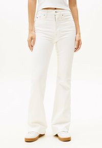 Pantalones vaqueros acampanados blancos hechos de una mezcla de algodón. Presentan un cierre de botón y cremallera, cinco bolsillos y una textura lisa y sin adornos.