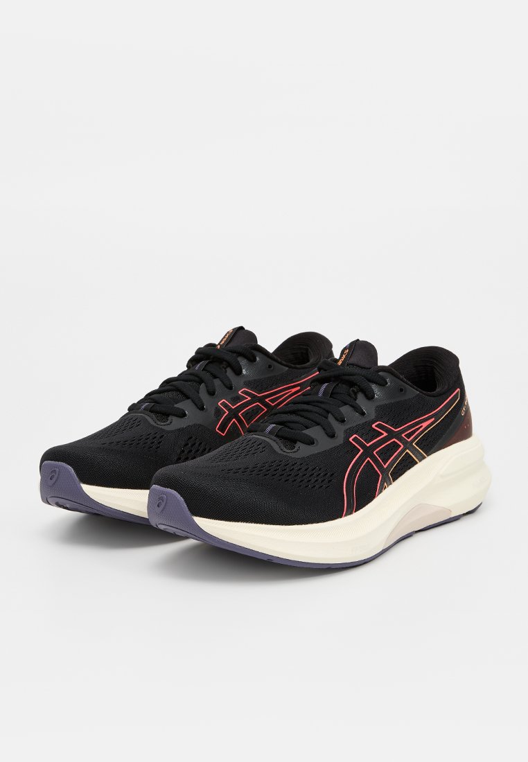 Zwarte sportieve schoenen met een ademende mesh bovenkant, voorzien van oranje en gele accenten, een gevoerde zool en een slank ontwerp.