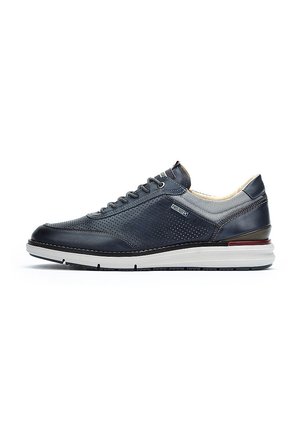 Baskets en cuir marine avec un design perforé, accents gris clair contrastants, col rembourré et semelle intercalaire blanche avec des détails rouges et noirs.