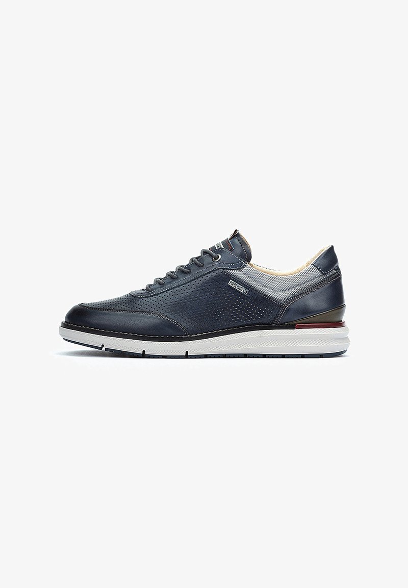 Baskets en cuir marine avec un design perforé, accents gris clair contrastants, col rembourré et semelle intercalaire blanche avec des détails rouges et noirs.