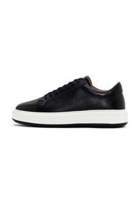 Black leather sneaker with a rounded toe, flat white rubber sole, and black laces. Smooth texture and minimalistic design.