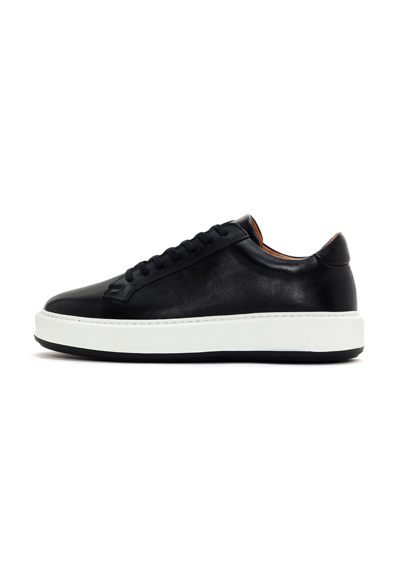 Black leather sneaker with a rounded toe, flat white rubber sole, and black laces. Smooth texture and minimalistic design.