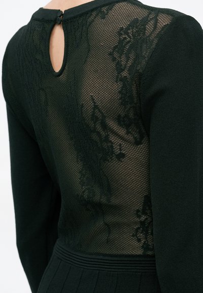 Vestido preto com costas em renda texturizada com padrões florais, detalhe em gota no pescoço e mangas longas em um design ajustado.