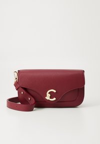 Dark red textured leather shoulder bag with a gold curved clasp and adjustable strap coiled beside it on a plain background.