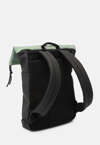 Svart ryggsäck med nätremmar och en mintgrön topp. Har en rulltoppdesign och justerbara remmar för komfort. Texturerad tyg.