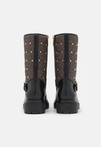 Svarta läder- och bruna mönstrade tygstövlar med guldnitar, dubbla dragkedjor och en chunky gummisula. Bakvy visar designdetaljer.